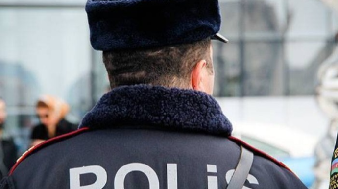 Bakıda parkda dekorativ daş uşağın üzərinə aşıb