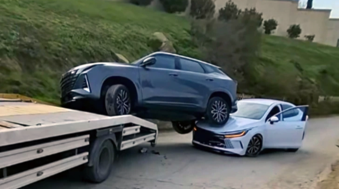 Evakuatorda daşınan avtomobil yolda hərəkət edən maşının üstünə düşdü - VİDEO 