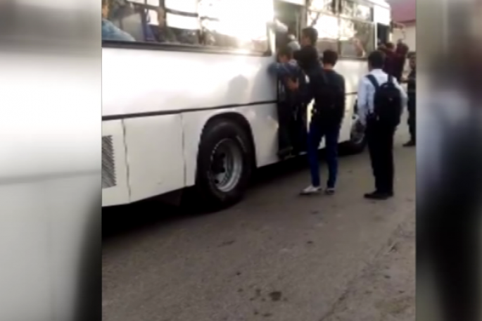 TƏHLÜKƏ: Şagirdlər qapısı açıq avtobusdan sallanaraq gedir - VİDEO